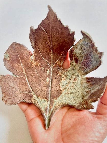 A beautiful, nature-inspired ceramic wall art piece. This one is shaped like a papaya leaf, with a rustic glaze that highlights the delicate vein details.