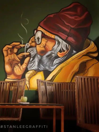 This mural of a man smoking was painted for a cafe in Goa. The realistic style and warm color palette create a relaxed, story-telling atmosphere for the space.