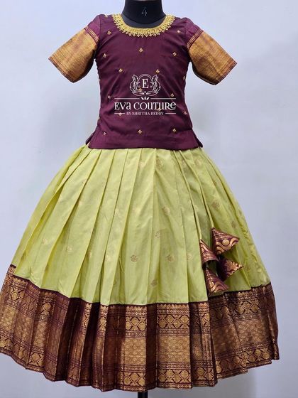 A simple and elegant Pattu Pavadai in wine and lime green. The blouse has subtle butti work, and the skirt has a traditional contrast border.