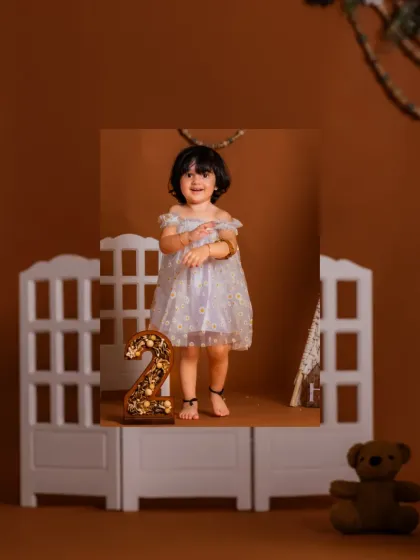 A vertical shot showcasing the full setup for a second birthday, complete with a rustic number '2' and a cute teepee.