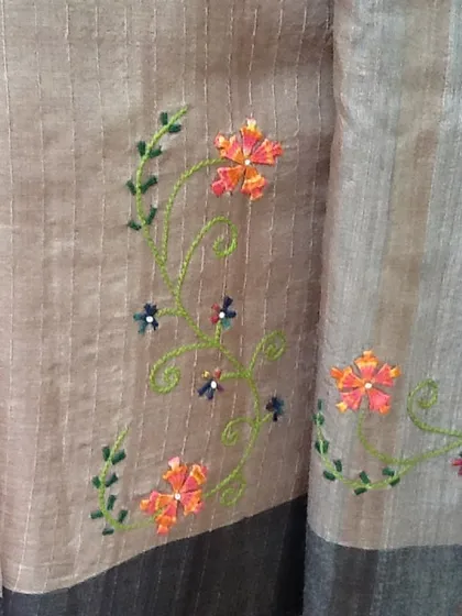 These are memories of past creations, showcasing delicate floral vines embroidered on a striped linen-blend saree. This kind of work is perfect for adding a touch of elegance to everyday wear.