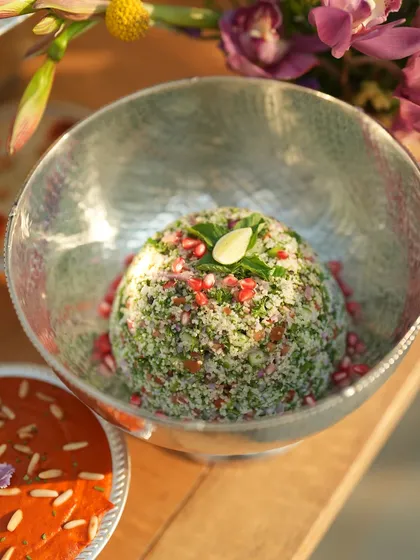 A beautiful bowl of tabbouleh, garnished with pomegranate seeds, part of the fresh and vibrant Mezze selection.