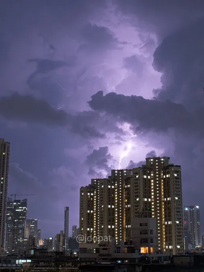 A lightning strike illuminates a massive, swirling cloud formation above Mumbai's skyscrapers during the monsoon.