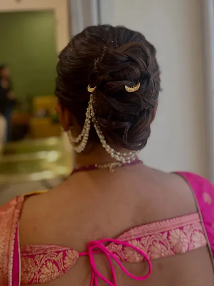 A closer look at the messy khopa, showing the interwoven textures and the placement of the pearl chain accessory.