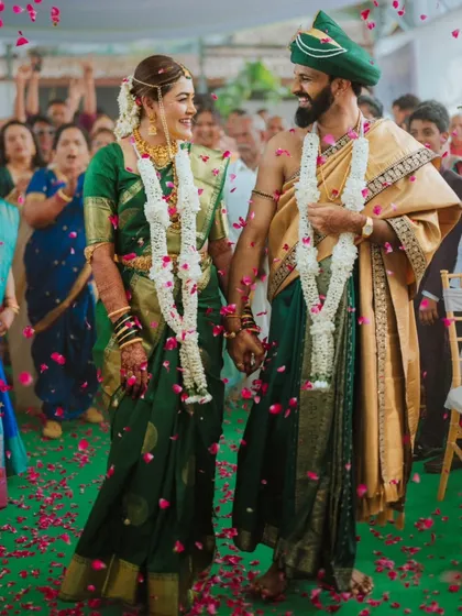 The couple walks hand-in-hand down the aisle, surrounded by family and a shower of petals, in a beautiful South Indian ceremony.