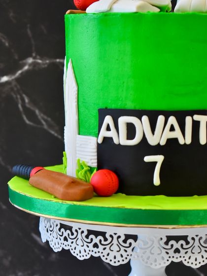 A detail shot of the cricket cake, focusing on the personalized scoreboard and the fondant bat and ball.