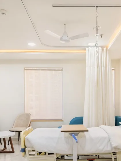 A patient room in the repurposed Sarvodaya Hospital, featuring clean lines, warm wood accents, and ample space for movement. The design focuses on patient comfort and dignity, with a dedicated seating area for visitors.