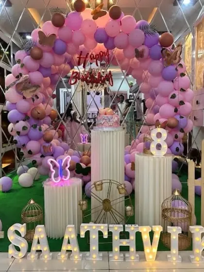 A pastel butterfly theme with a mirrored backdrop that adds depth and reflection. The setup includes a neon butterfly sign and marquee letters.
