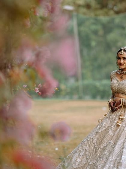 A beautiful, artistic shot of the bride in a garden, framed by soft pink flowers.