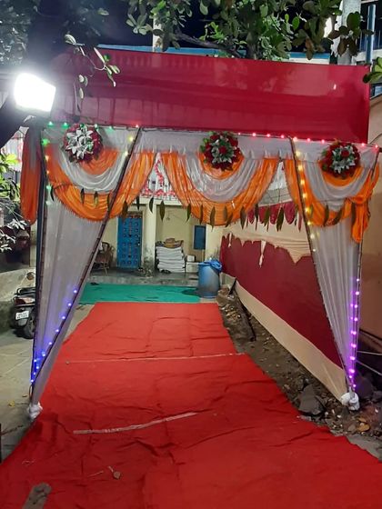 An entrance to a pandal for a night event, with a red carpet runner and simple lighting.