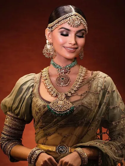 A smiling portrait of a South Indian bride. The makeup is traditional and elegant, but her happy expression shows she feels comfortable and beautiful.