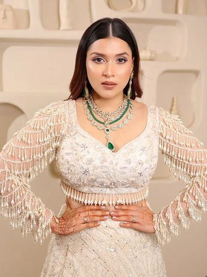 A confident pose in our white pearl lehenga, paired with a stunning layered emerald necklace. This look is a perfect fusion of traditional jewelry and contemporary attire.