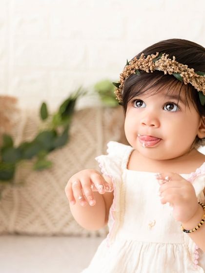 A sweet, candid close-up of a baby girl tasting frosting for the first time during her boho-themed cake smash.