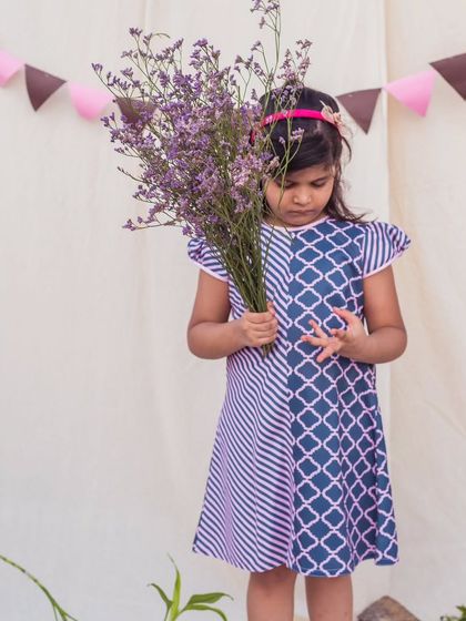 A thoughtful moment in a stylish printed dress. The mix of diagonal stripes and a geometric pattern creates a visually interesting and modern look.