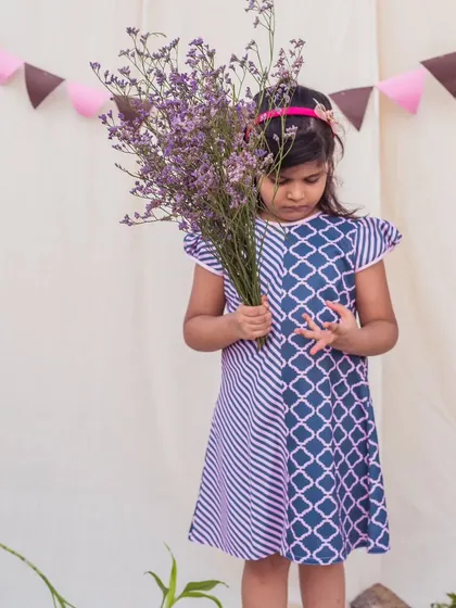 A thoughtful moment in a stylish printed dress. The mix of diagonal stripes and a geometric pattern creates a visually interesting and modern look.