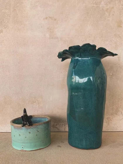 A collection of two finished vases, one with a wild petal top and another with a charming bird perched on the rim.