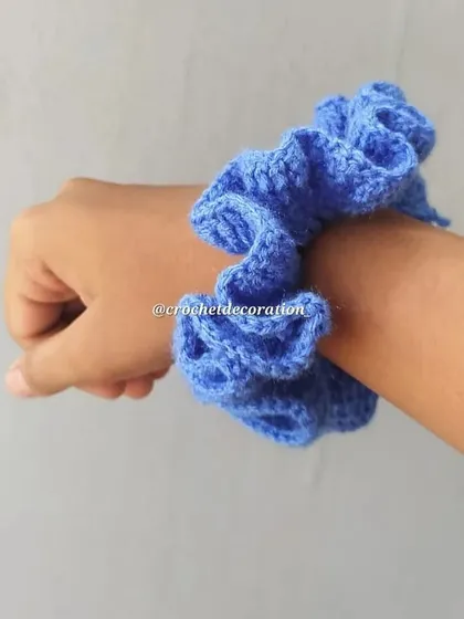 The crochet scrunchie worn on a wrist. It's a stylish and comfortable accessory, available in a variety of colors to match your outfit.