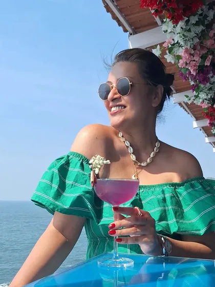 Enjoying a cocktail by the sea in Goa. This off-the-shoulder green striped dress is perfect for a beachside bar, paired with a shell necklace to complete the tropical vibe.