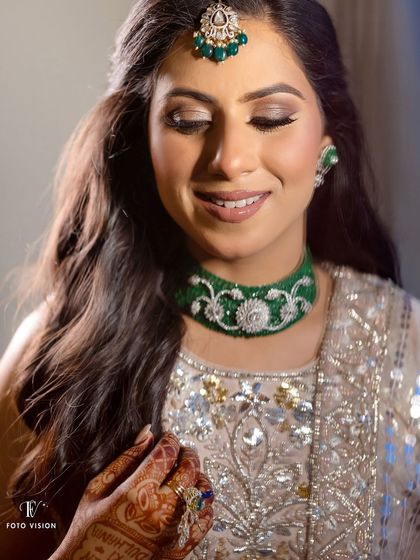 A beautiful close-up of the bride, highlighting her elegant green choker necklace and soft, glamorous makeup.