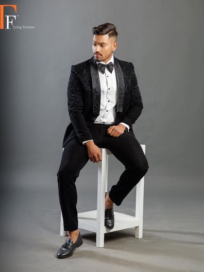 A model looking sharp in a black velvet tuxedo with a subtle, intricate pattern. This is a perfect choice for a groom who wants a unique texture.