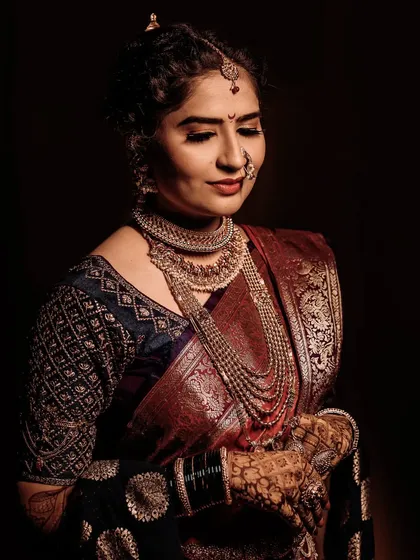 A dramatic, low-key portrait that brings all the focus to the bride. The rich colors of her saree and her calm expression create a powerful and elegant image.