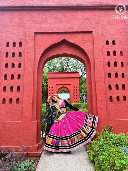 A full-length shot showcasing the beautiful flare of the Navratri ghagra against a vibrant red backdrop. This look is all about celebrating with color and style.