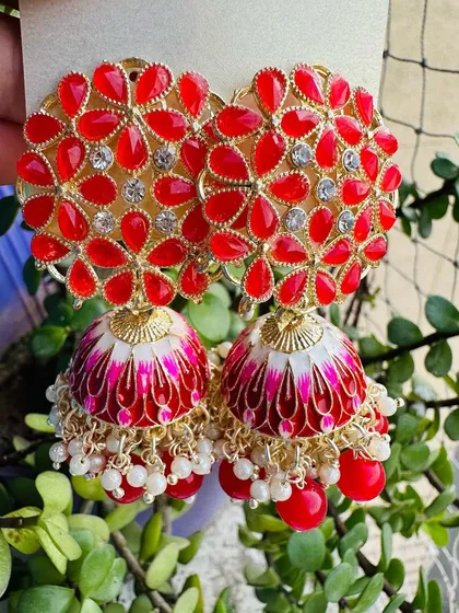 A classic combination of red and gold. These jhumkas feature red enamel work on a floral stud and dome, accented with small pearls for a traditional yet stylish feel.