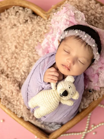 This sleeping beauty is perfectly content with her little teddy bear. The soft lighting and cozy setup ensure the baby's comfort and safety.