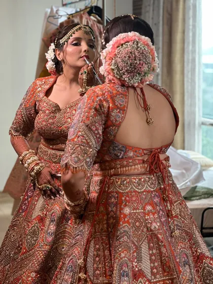 A behind-the-scenes shot of a bride getting her final touches, with a beautiful floral bun in the mirror's reflection.