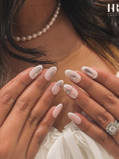 Elegant and festive nail art for a sophisticated holiday look. This design features delicate, hand-drawn silver bows and starbursts on a soft, natural base, perfect for any Christmas party.