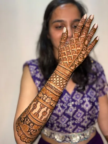 A single-hand view of a bridal back-of-hand design. The intricate grid pattern and delicate motifs create a stunning and elegant look.
