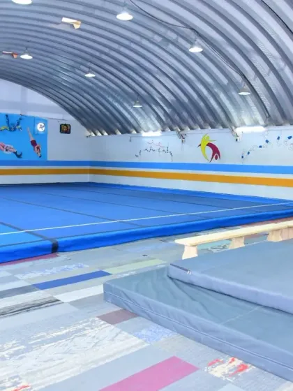 Welcome to our home. A glimpse of our clean, spacious, and well-equipped training facility, featuring a full-size floor, balance beams, and safety mats for our gymnasts.