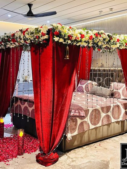 This view highlights the full effect of the romantic bedroom decor. The combination of red velvet, fresh flowers, and soft lighting creates a truly special and memorable ambiance for the couple.