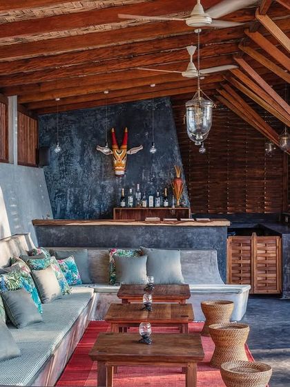 The bar and lounge area by the main pool, built with an exposed timber frame and a large, built-in sofa. It's a social space designed for relaxation, reflecting the laid-back luxury of the hotel.