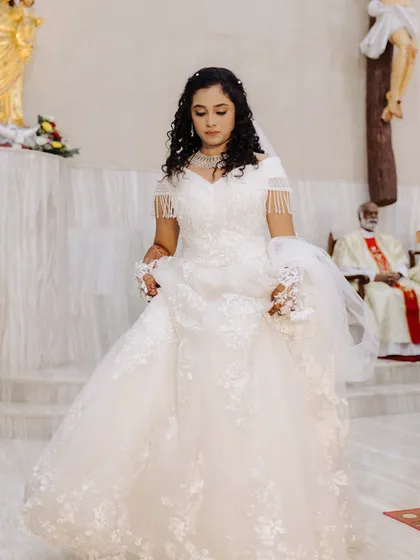 A full-length view of the bride in the church. Her gown and her makeup create a picture of pure elegance and grace.
