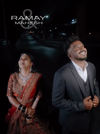 A candid, happy moment captured during a night shoot. The couple is dressed in their reception lehenga and suit, looking up at the sky.