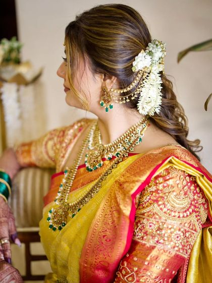 A beautiful half updo with soft curls, adorned with a gajra and a traditional hair accessory. This is a popular style for South Indian pre wedding events.