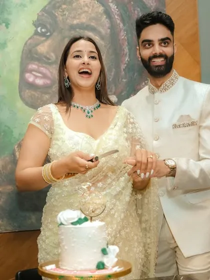 A joyous cake-cutting moment during an indoor engagement celebration in Pune. The couple's happiness is the focus, framed by modern decor and a beautiful piece of art, capturing the celebratory spirit of the occasion.