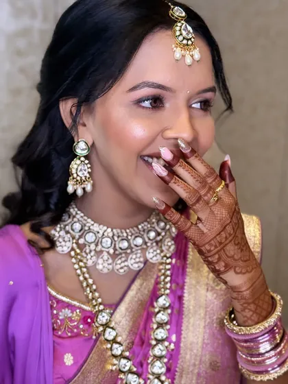A joyful moment captured during her engagement. The makeup is soft and radiant, highlighting her smile and the intricate henna design.