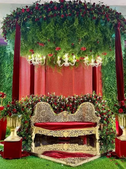 For this Nikah, we designed a grand and royal stage. A massive canopy of greenery and red roses hangs above an ornate gold and red velvet sofa, creating a breathtaking focal point for the ceremony.