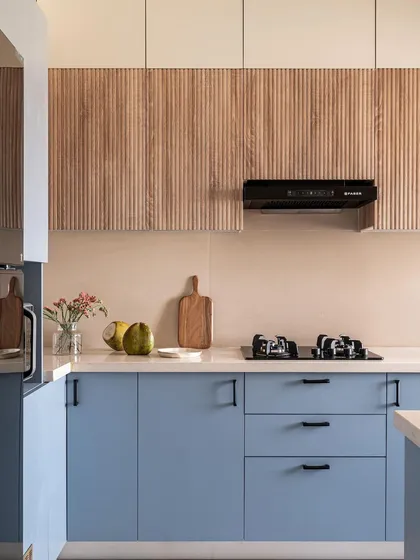 A detailed shot of the custom kitchen cabinetry, highlighting the contrast between the smooth matte blue finish and the vertical lines of the fluted upper cabinets. Black hardware adds a modern, graphic touch.