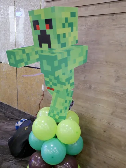 A custom-made cutout of a Creeper character from Minecraft, placed on a balloon base. These props are essential for bringing a video game theme to life.