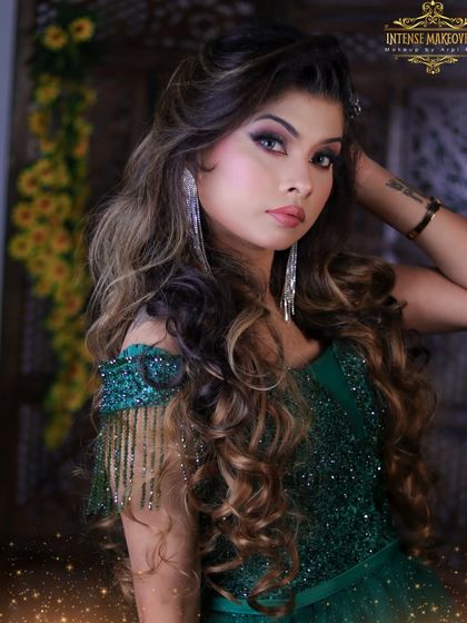 A captivating look for any special event. This model is showcasing a glamorous style with voluminous curls and a stunning green sequined dress.