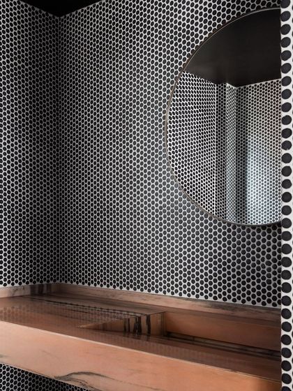 A powder room featuring a custom wash basin I designed from pink Makrana marble. The basin's trough-like shape is set against a backdrop of bold penny tiles, creating a dramatic and memorable space.