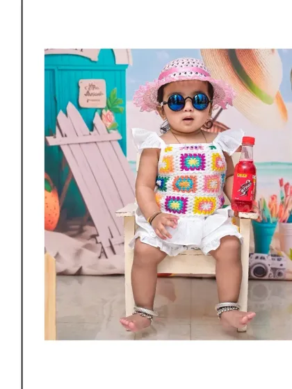This little girl is ready for her beach-themed birthday party, looking cool in her sunglasses, hat, and colorful top. Themed birthday shoots are a fun way to celebrate your child's personality.