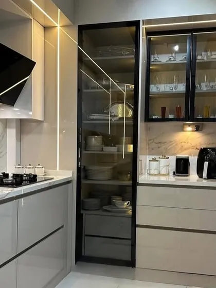 Lighting and storage are key to luxury kitchen design. This project features a stunning floor-to-ceiling glass pantry with internal lighting, complemented by vertical light strips and under-cabinet spotlights to create a warm, inviting, and highly functional space.