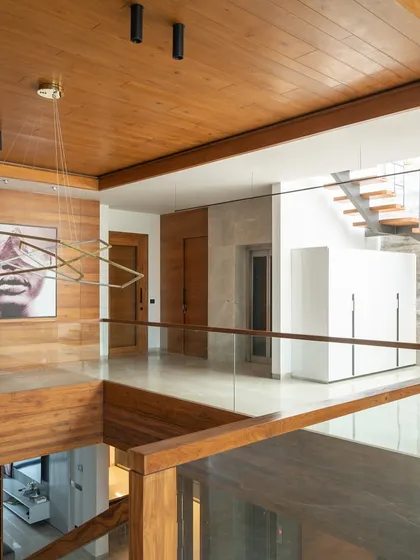 A stunning double-height space featuring sleek wooden accents, a modern art piece, and a glass bridge, creating a powerful sense of openness and modern style.