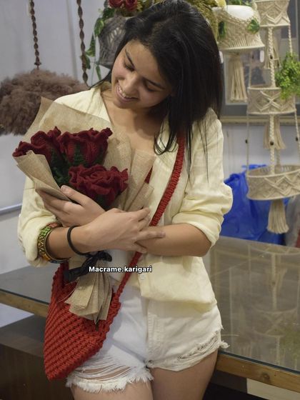 Modeling our red heart-shaped macrame bag. It's a bold and unique accessory, perfect for making a statement.