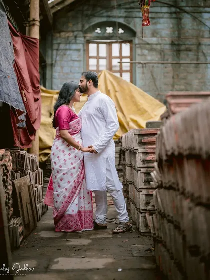 A quiet forehead kiss in an unexpected location. The rustic, industrial setting provides a unique and textured backdrop for this tender pre-wedding moment.