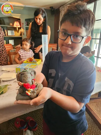 A young boy proudly displays his beautifully crafted and decorated Ganesha idol. The concentration and pride on his face say it all.